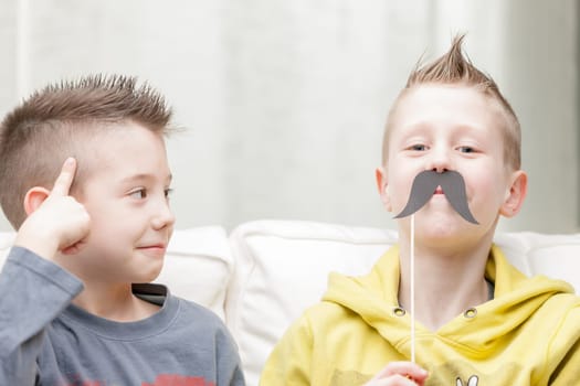 couple of little brothers making funny faces with fake moustaches