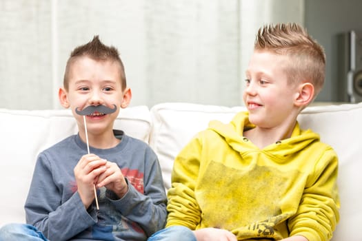 couple of little brothers making funny faces with fake moustaches