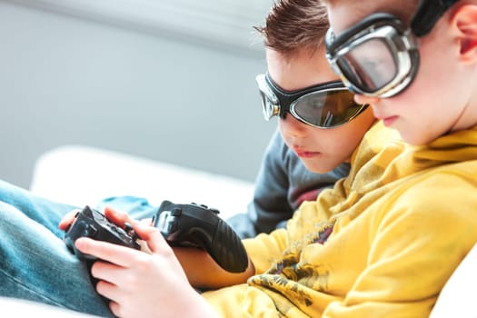 Two young brothers siting on a sofa playing video games in a close up cropped view as they check out their controllers or joysticks with copyspace