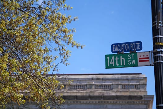Green 14th Street South West historic sign in downtown Washington D.C. with Evacuation Route blue sign and the three stars with the building on the back