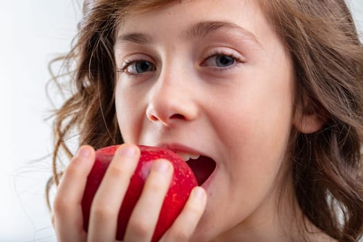 Young schoolgirl about to bite into a luscious red apple in a close up cropped sensual view in a healthy eating and diet concept