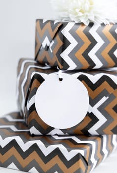 Presents with blank round gift tag close up. Gift boxes wrapped in chevron geometric paper. Christmas, New Year, Birthday, Anniversary label mockup