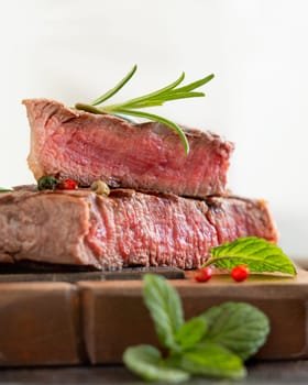 Grilled beef fillet steaks on dark table close up. Portioned filet mignon with spices and herbs. Concept of summer food, meat eaters.