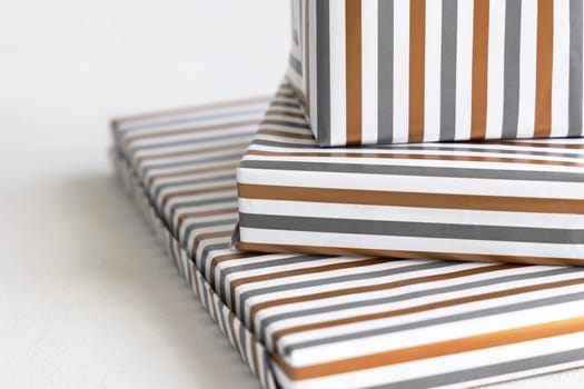 Presents Wrapped in striped geometric paper on white table close up. Christmas, New Year, Birthday, Anniversary concept