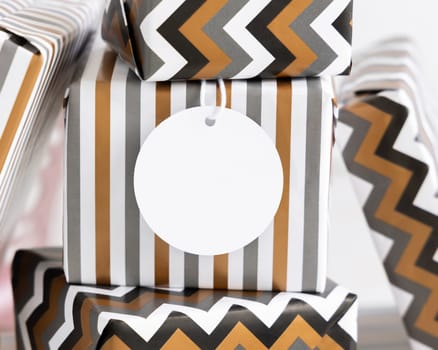 Present with blank round gift tag close up. Gift boxes wrapped in Striped and chevron geometric paper. Christmas, New Year, Birthday, Anniversary label mockup