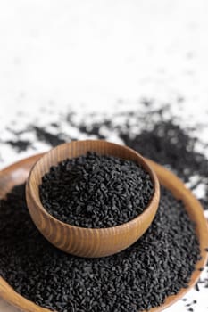 Indian spice Black cumin (nigella sativa or kalonji) seeds in wooden bowls close up with copy space. Traditional medicine, healthy and vegetarian food concept.