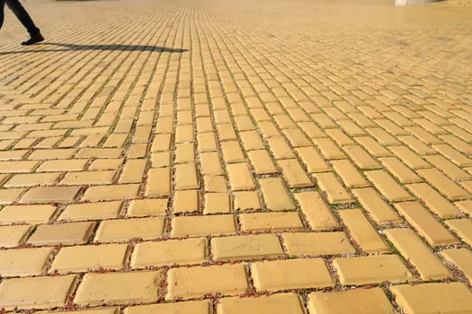 Yellow cobblestone, brick road in Sofia, shadow of pedestrian in the background, Bulgaria 2021