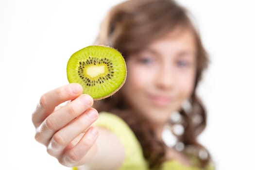 Young girl holding up a slice of fresh kiwi fruit on display to the camera with focus to the kiwifruit in a healthy diet concept
