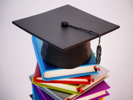 Mortarboard standing on stack of colorful books. 3D illustration.