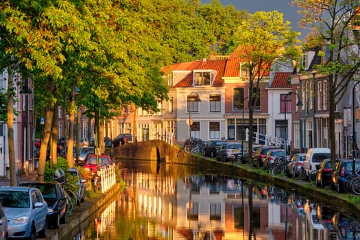 Delt canal with old houses and cars parked along on sunset. Delft, Netherlands
