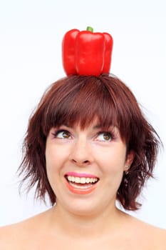 A laughing young woman with a red bell pepper on her head