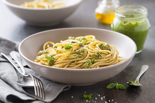Served hot spaghetti with fresh basil pesto and herbs closeup