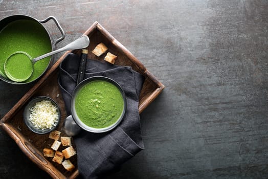 Fresh vegetable cream soup with parmesan cheese and croutons on grey background overhead shoot.