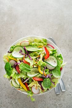 Green lettuce salad with fresh mixed vegetables on grey table background