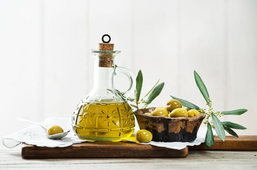 Olive oil bottle and olive branch with Pickled green olives on wooden table