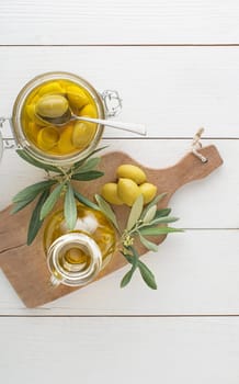 Olive oil bottle and olive branch with Pickled green olives in glass jar on the wooden table