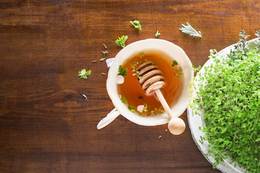Tea Cup of fresh herbal leaves with honey on wooden background, top view, place for text. Healthy concept