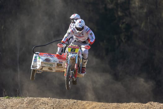 MOHELNICE, CZECH REPUBLIC - APRIL 16, 2022. The winners of the race are in a high jump on a dark background in the "Sidecarcross Championship of Czech Republic"" on April 16, 2022 in  Mohelnice."