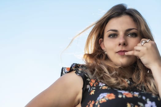 Portrait of beautiful  young woman posing outdoors against blue sky. Horizontally.