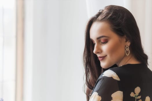 Side view portrait of  attractive smiling girl with lowered eyes  indoors. Horizontally.