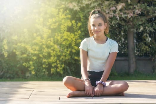 Cute tanned girl is posing in the summer garden. Horizontally.