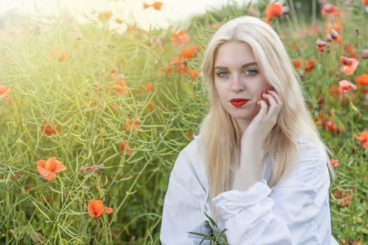 Smiling attractive  long hair young woman is posing in a poppy field. Horizontally.