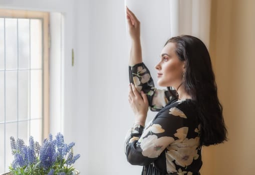 Side view portrait of atractive dark haired girl looking from the window. Horizontally.