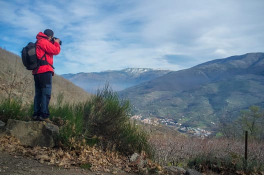 Trekker man taking picture to Jerte Valley on winter. Navaconcejo, Caceres, Extremadura, Spain