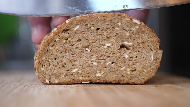 Slicing Whole Grain Bread On Wooden Table.