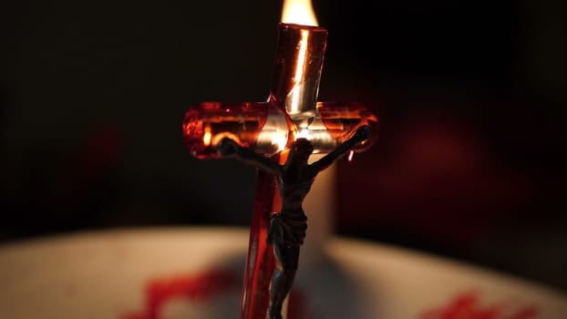 Close up of cross of jesus with blood lit by candle