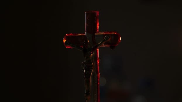 Close up of cross of jesus with blood lit by candle..