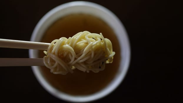 Close up of instant noodles yellow ramen on Chinese chopsticks.