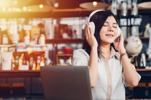 Business women lifestyle freelance sitting alone he using earphones listening music new song during working on laptop computer in coffee cafe shop, Student girl coffee break while doing homework