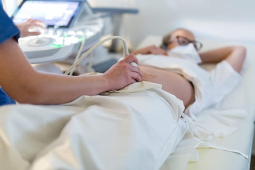 Close up of a pregnant woman having ultrasound scanning at the medical clinic. Healthcare and medicine concept.