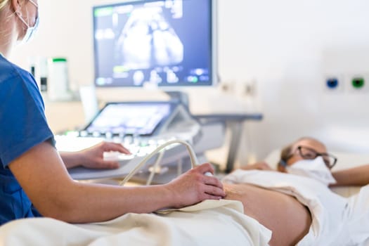 Close up of a pregnant woman having ultrasound scanning at the medical clinic. Healthcare and medicine concept.