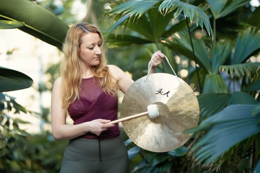Yoga concept, meditation and sound therapy. Beautiful young caucasian woman performing tibetan gong music therapy