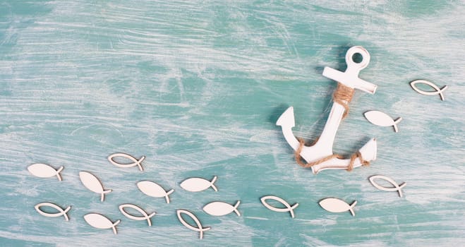 White anchor and fish on a blue background, maritime sea life, sailing trip, summer vacation, tourism concept, harbor
