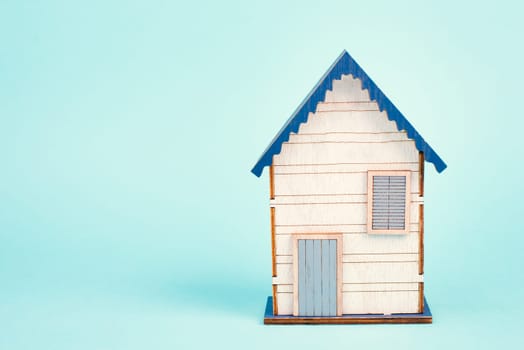 Wooden house, blue background, buying or renting a house, real estate concept, booking home for vacation, copy space for text