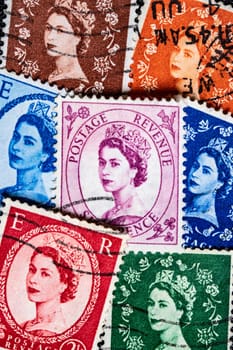 Potsdam, Germany - APR 26, 2022. A set of vatious vintage postage stamps printed in United Kingdom   shows Queen Elizabeth II, Queen of the United Kingdom. Macro.