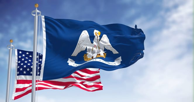 The Louisiana state flag waving along with the national flag of the United States of America. In the background there is a clear sky. Louisiana is a state in the Deep South regions of the US