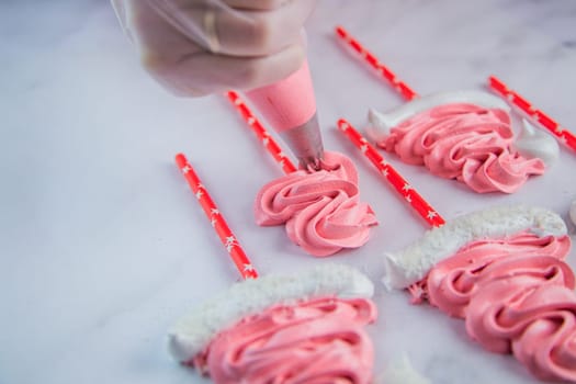 From the pastry bag, the pastry chef squeezes out a zigzag meringue on white parchment and a red stick. High quality photo