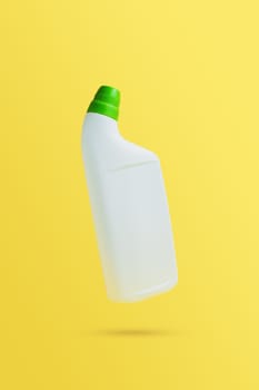 Levitating or flying blank toilet cleaner bottle with green cap. Isolated on yellow background. White plastic packaging. Household chemistry. Front, side view. Falling single object in air with shadow