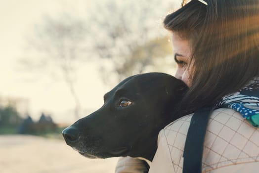 Young woman kissing her dog. Retro filter.
