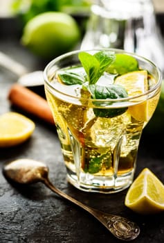 Mojito cocktail and ingredients on dark table