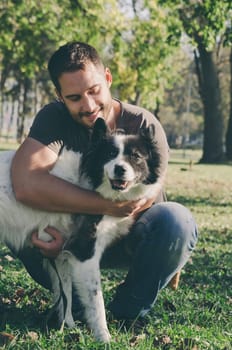 Happy man and his dog play in the park. Retro filter added.