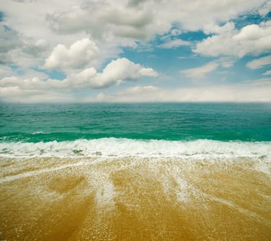 Sandy beach, sea and blue sky with clouds.