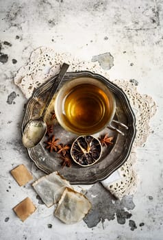 Cup of tea with anise seed on silver plate.