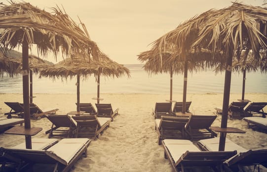 Sun umbrellas and sunbeds on beautiful sandy beach. Retro filter.