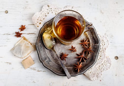 Cup of tea with anise seed on silver plate.