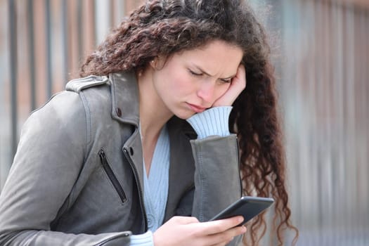 Confused woman checking smartphone in the street